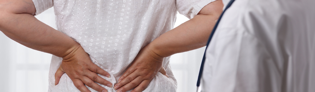 Woman holding her lower back in pain due to pelvic organ prolapse.