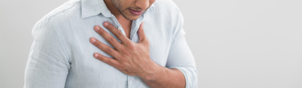 Man holding chest from burning sensation caused by GERD (acid reflux).
